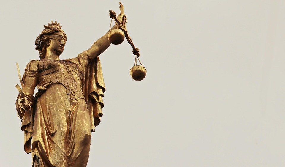 Eine Justitia-Statue vor einem weißen Hintergrund.